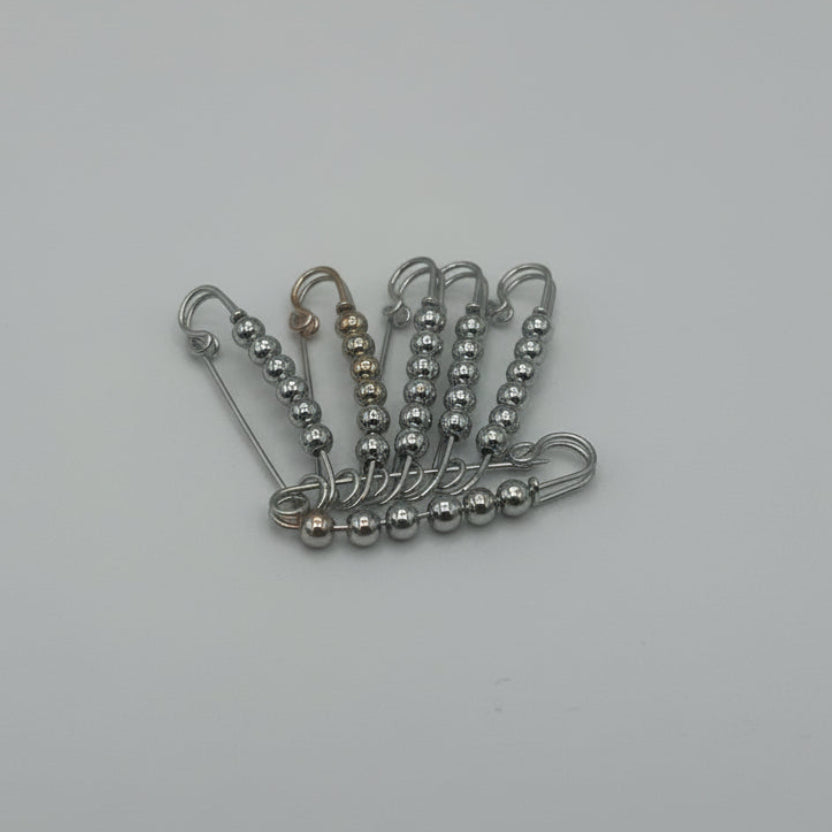 Metallic safety pins on a white background 