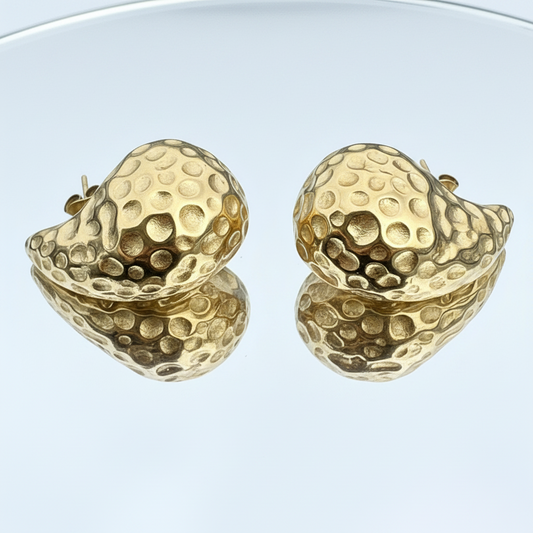Gold textured sphere earrings on a reflective surface