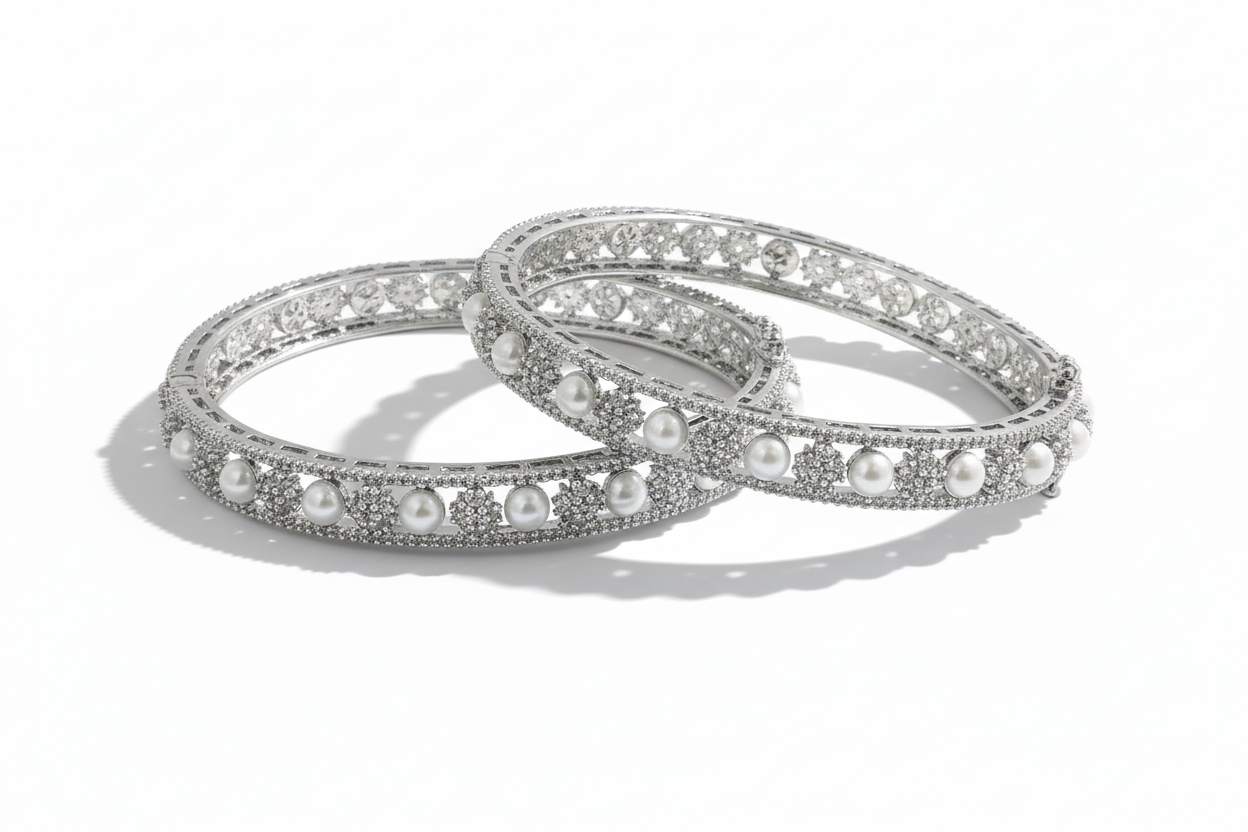 Two silver bangles with pearl beads on a green background