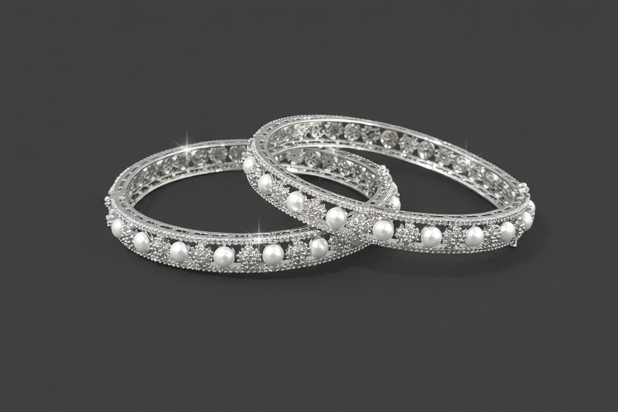 Two silver bangles with pearls on a black background