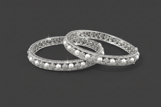 Two silver bangles with pearls on a black background