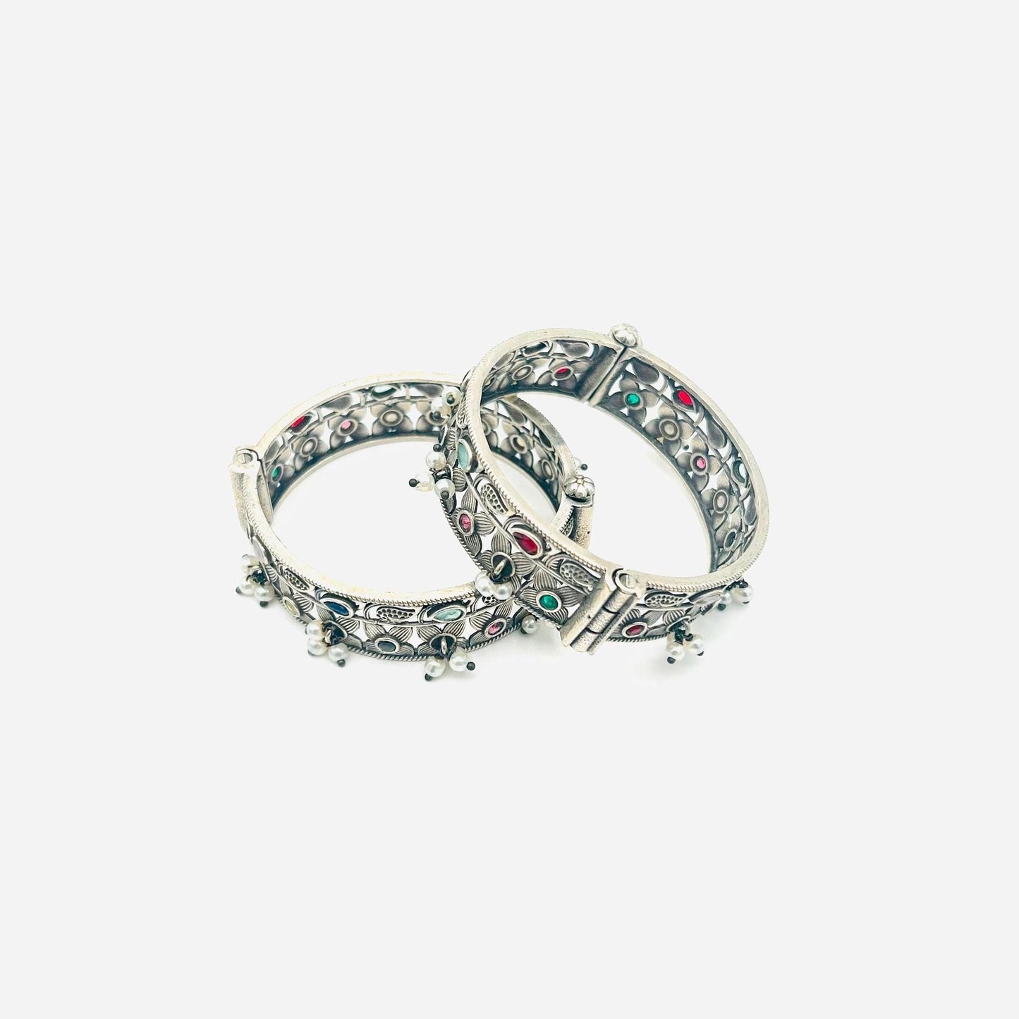 Pair of silver bangles with gemstone accents on a white background