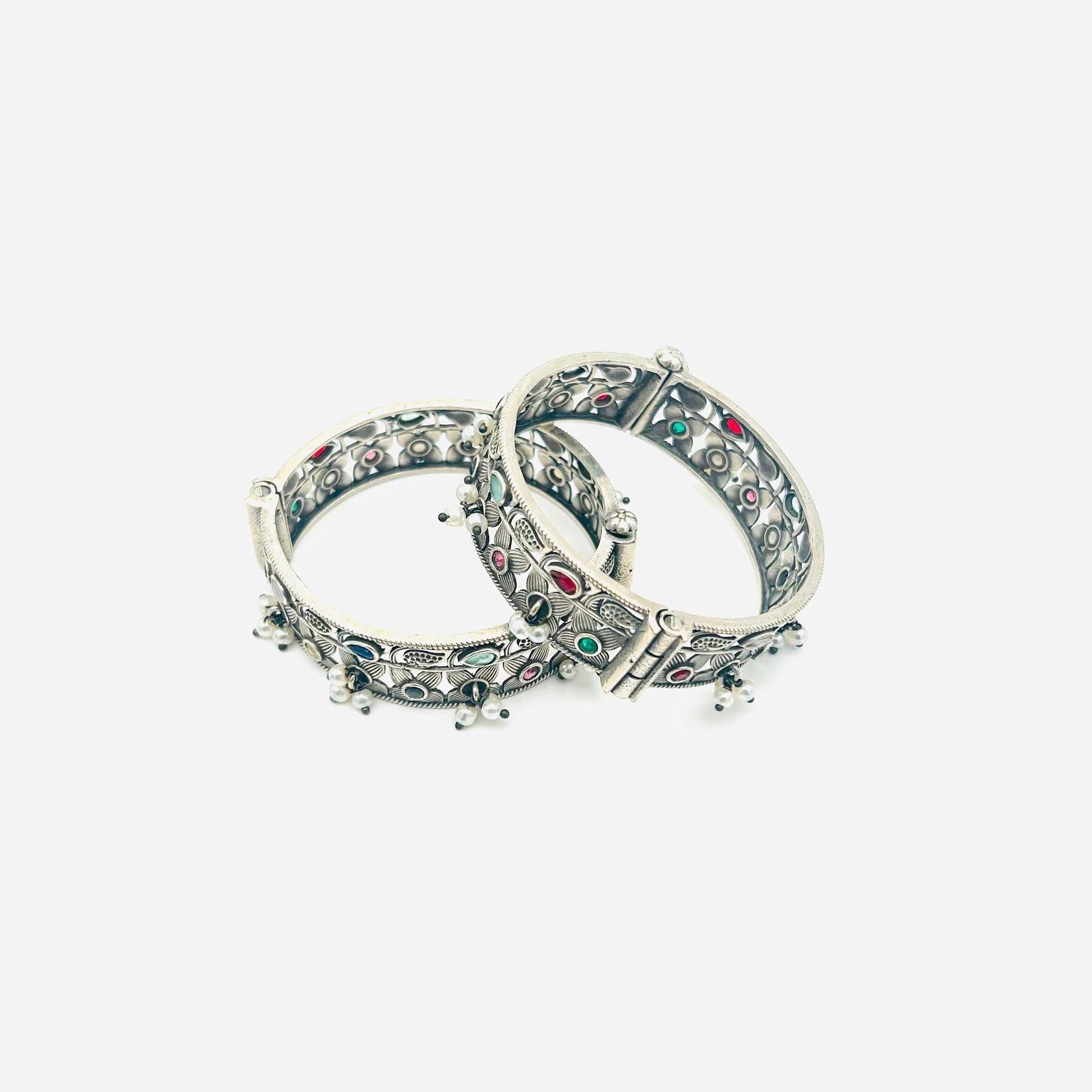 Pair of silver bangles with gemstone accents on a white background
