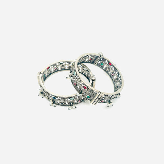 Pair of silver bangles with gemstone accents on a white background