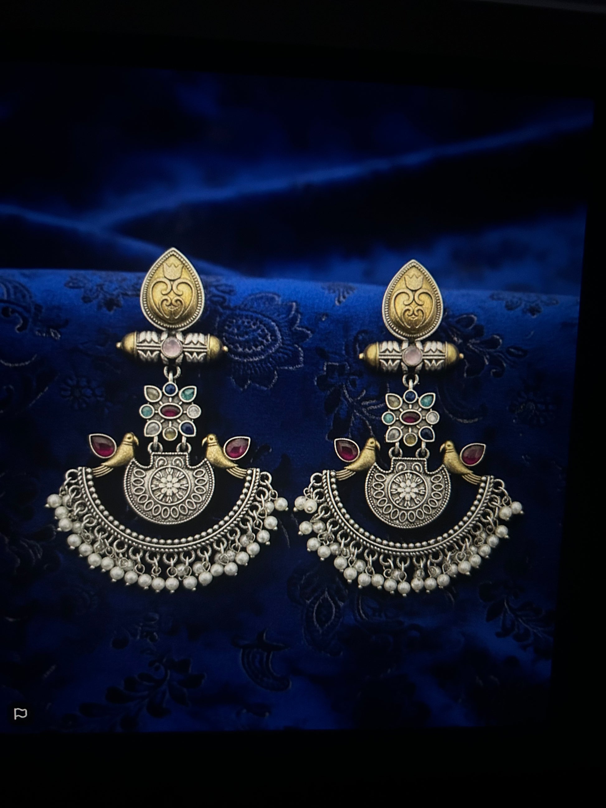 Ornate earrings on a dark blue fabric background