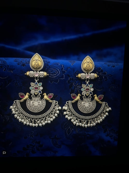 Ornate earrings on a dark blue fabric background