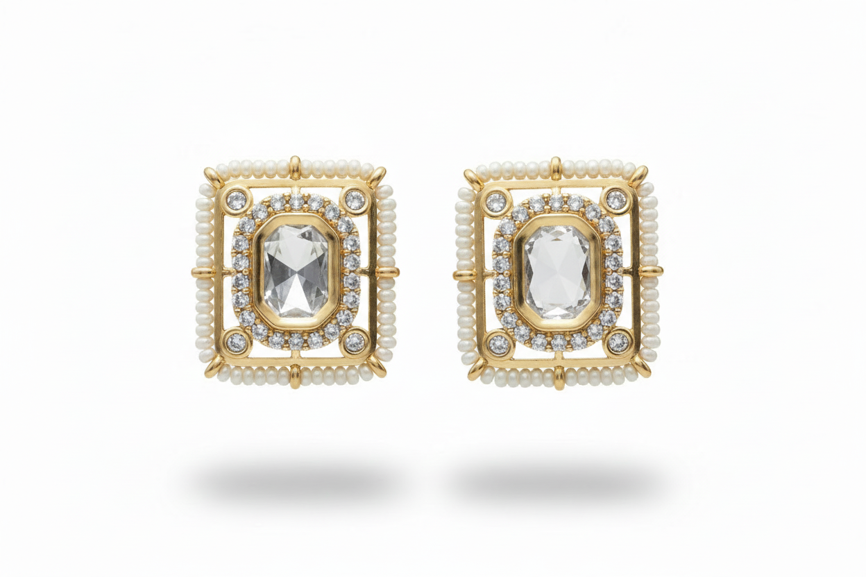 Pair of kundan gold plated earrings with central gemstones on a white background