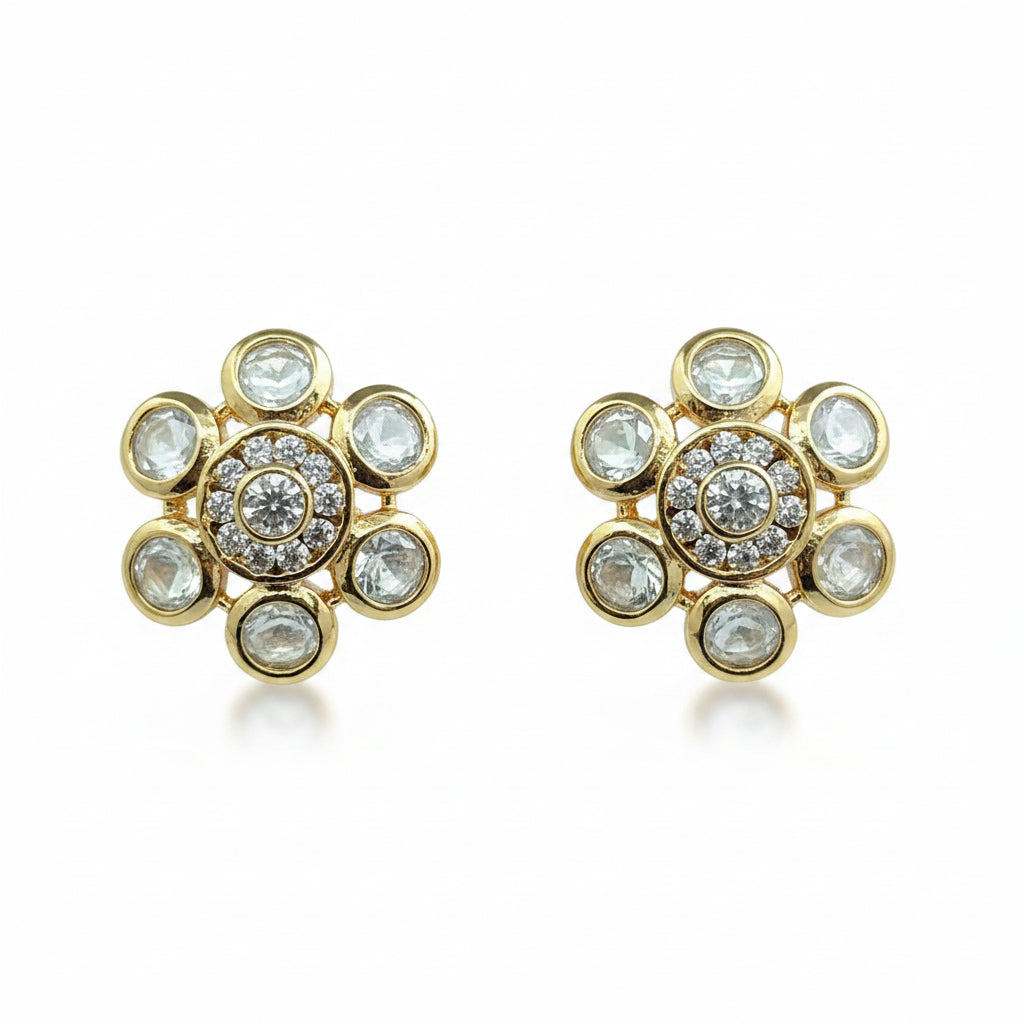 Pair of gold floral earrings with gemstones on a purple background