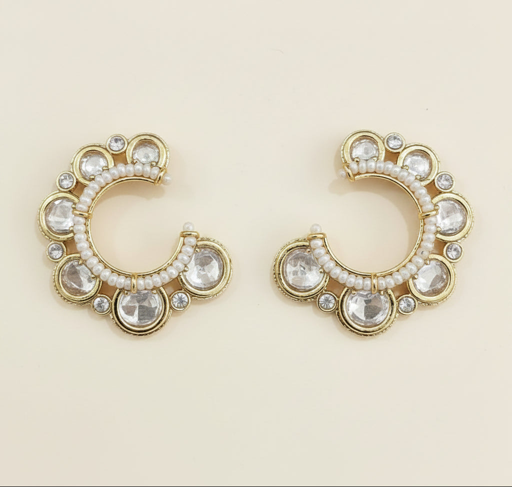 Pair of gold hoop earrings with clear gemstones on a blue background