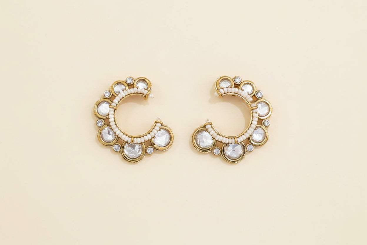 Pair of gold hoop earrings with pearls and crystals on a light being background
