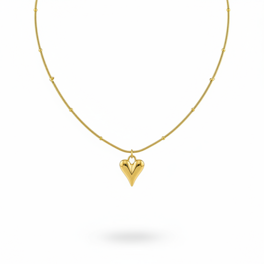 Gold necklace with a heart-shaped pendant on a white background