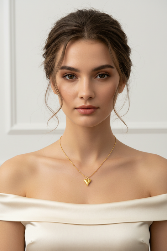 Woman wearing a gold necklace with a heart pendant against a white background