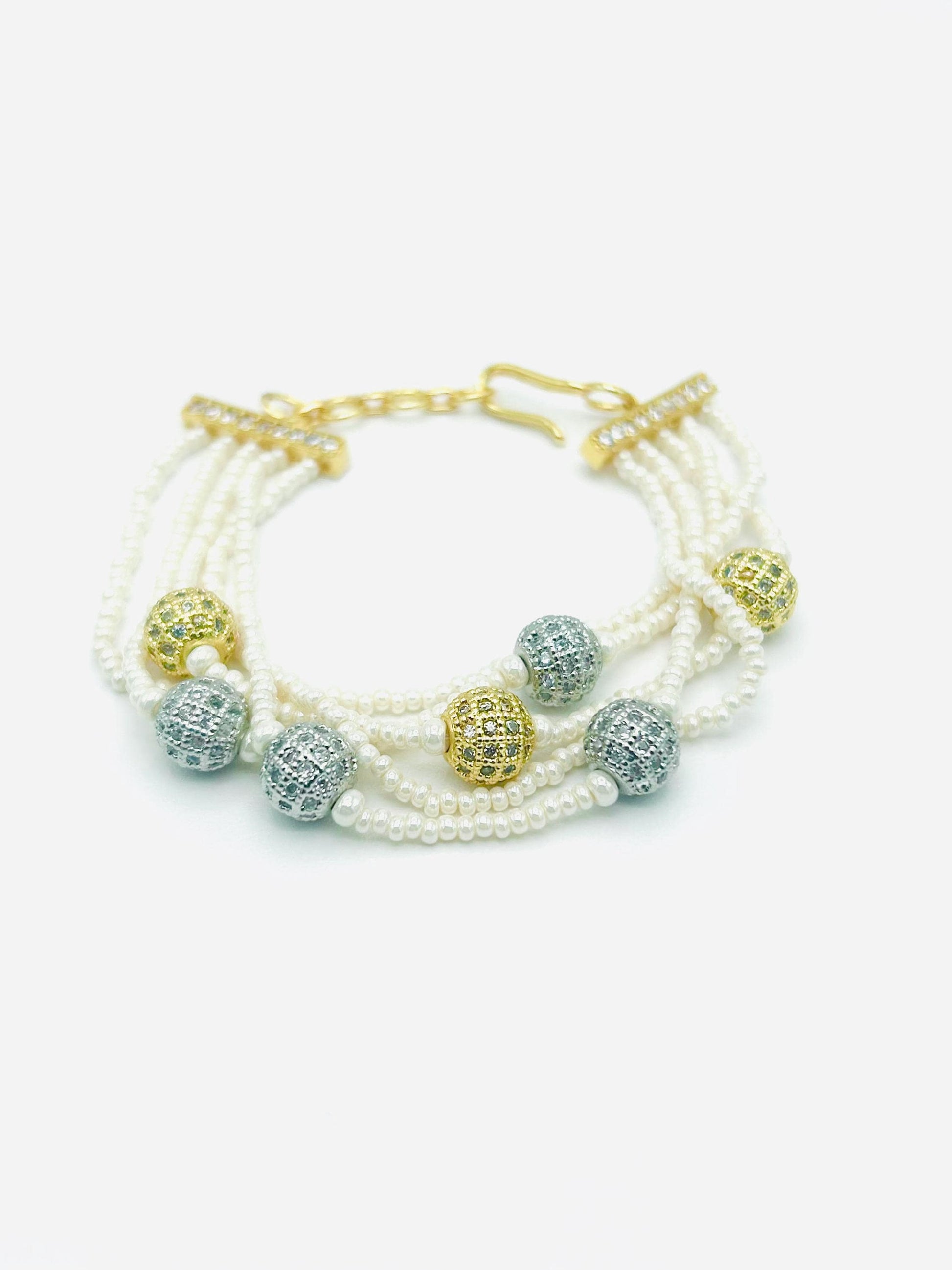 Multistrand pearl bracelet with gold and silver beads on a white background