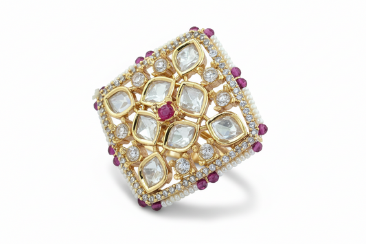 Gold plated ring with diamond and ruby stones on a white background