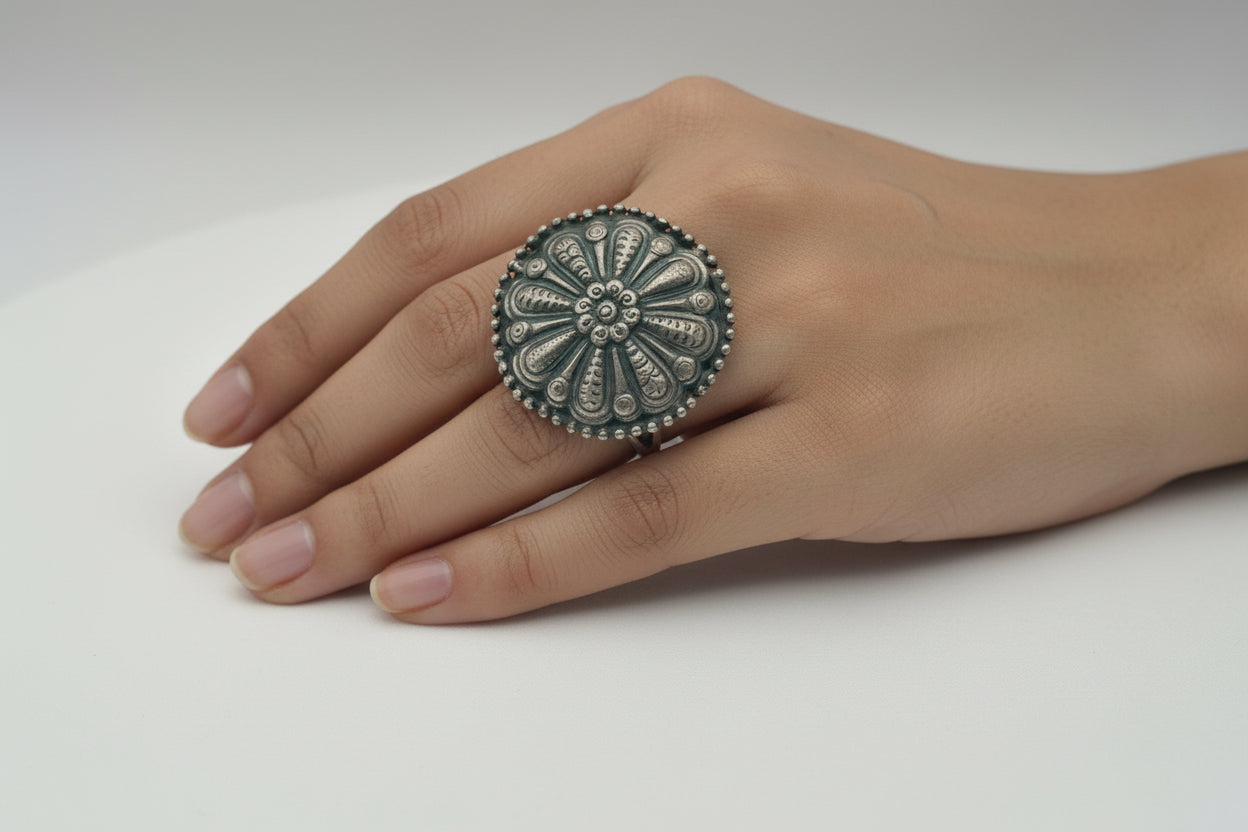 Silver ring with floral design on a hand against a white background