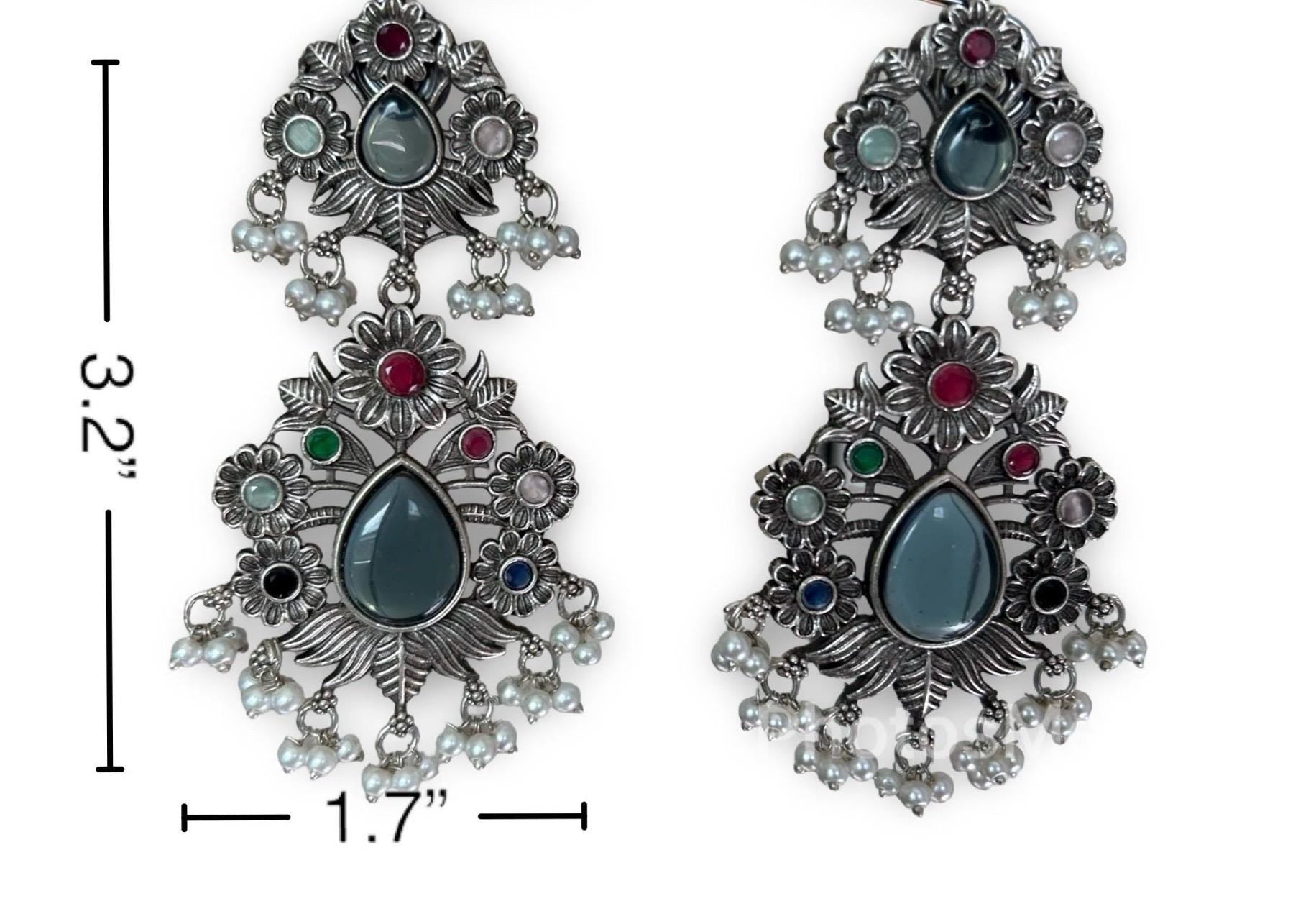 Ornate earrings with gemstones and measurements on a white background