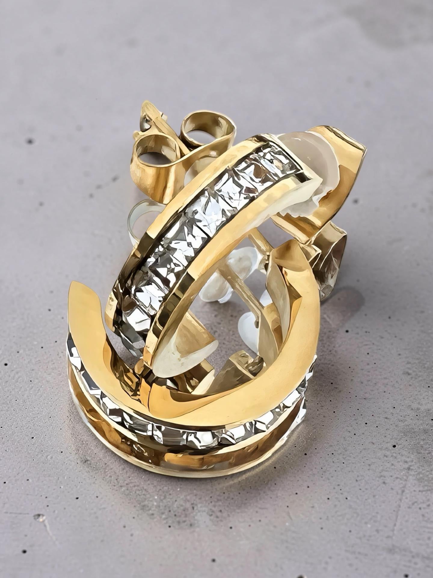 Gold and crystal earring on a gray surface
