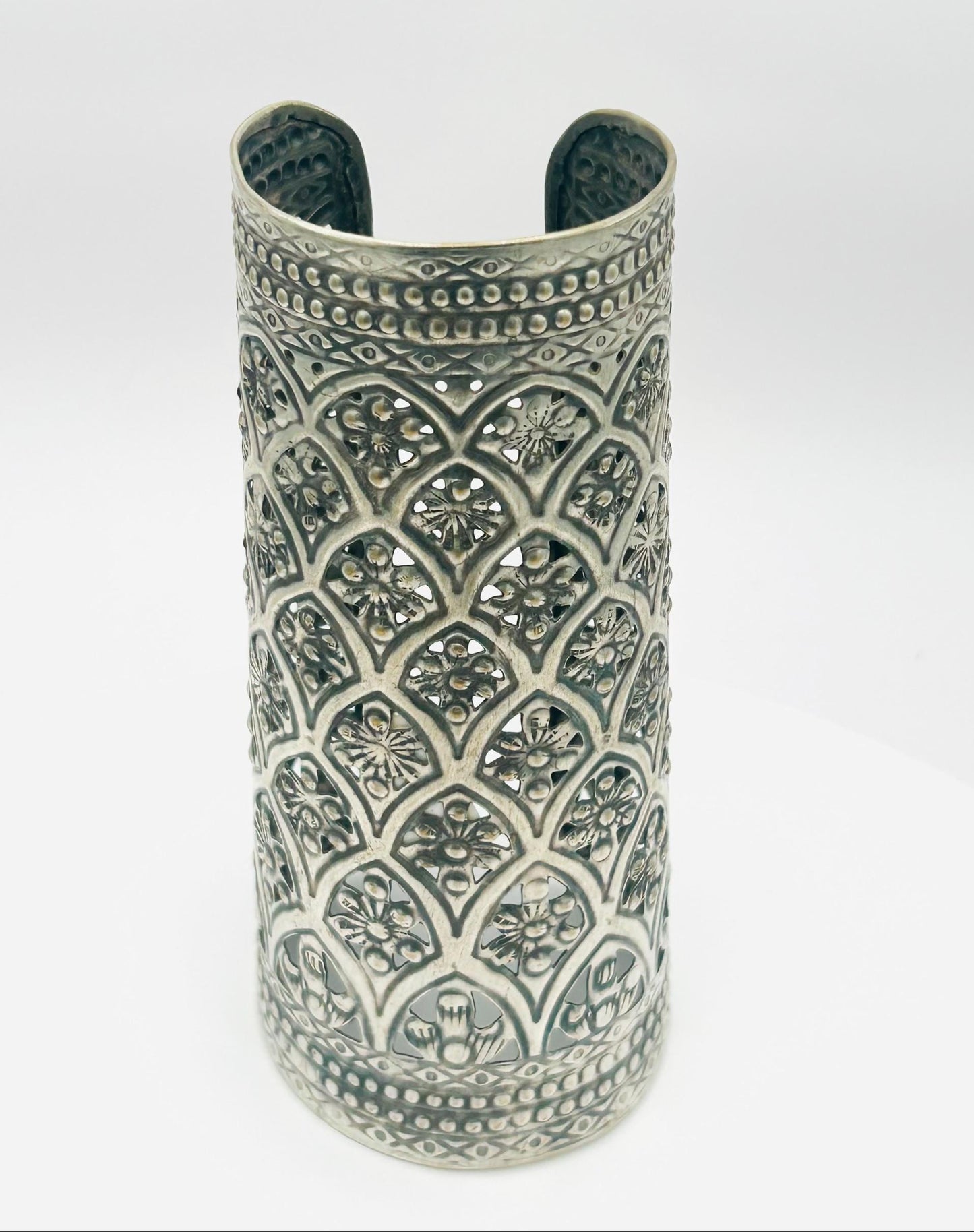 Silver cuff bracelet with intricate patterns on a white background