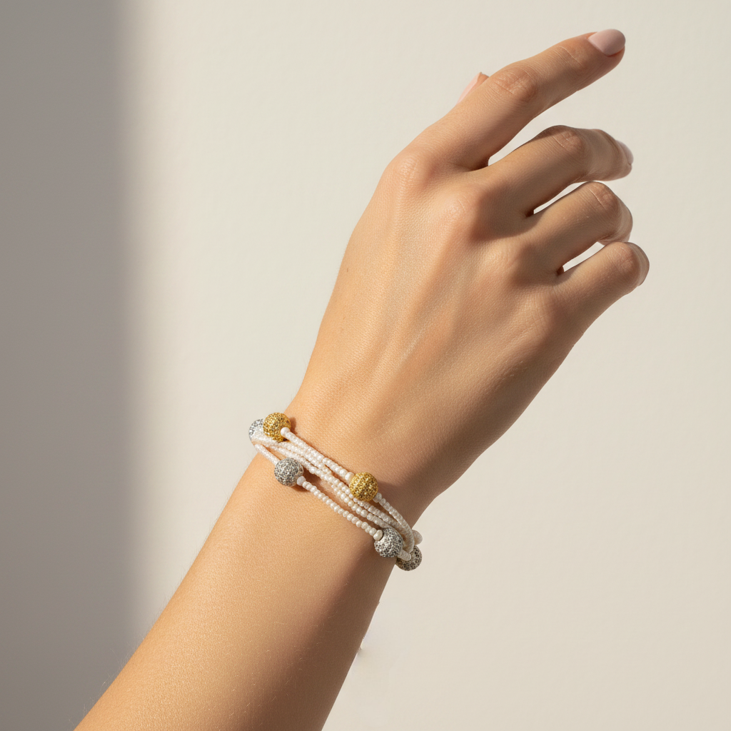 Women Hand wearing a pearl multi layer statement bracelet with gold and silver beads casual traditional jewelry on a neutral background