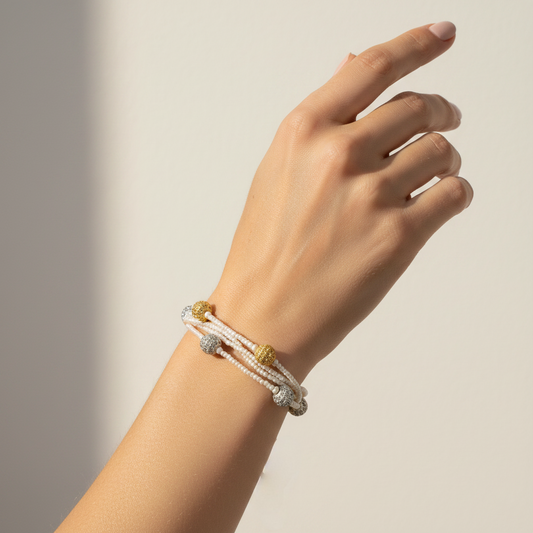 Women Hand wearing a pearl multi layer statement bracelet with gold and silver beads casual traditional jewelry on a neutral background
