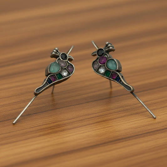 Pair of silver ear cuff earrings with gemstones on a white background