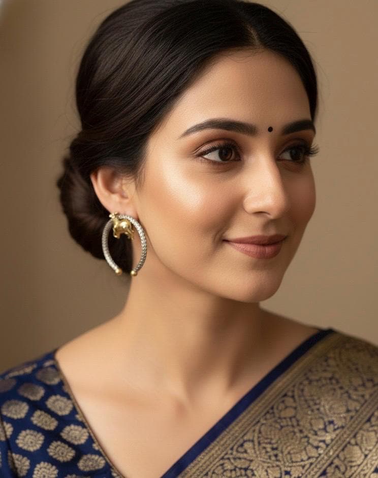Woman wearing a blue saree with gold patterns against a beige background