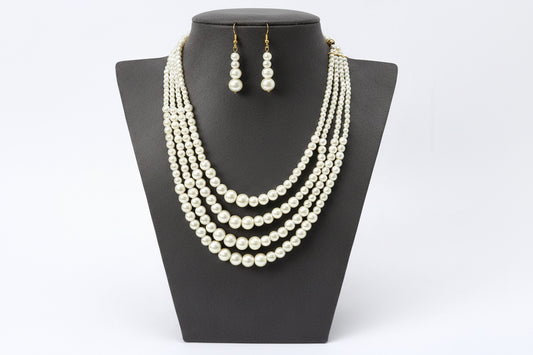 Pearl necklace and earrings set on a beige mannequin bust against a white background