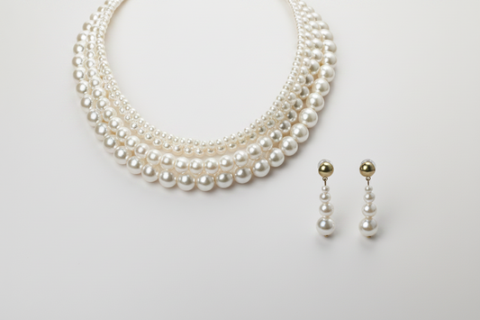 Pearl necklace and earrings on a light gray background