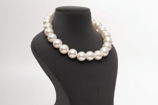 Pearl necklace on a mannequin bust against a plain background