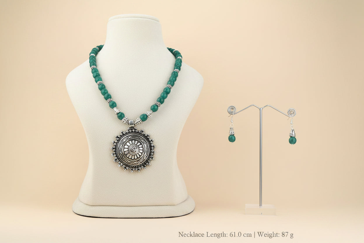 Jewelry set with oxidize vintage pendant necklace and earrings on a mannequin and stand against a white background