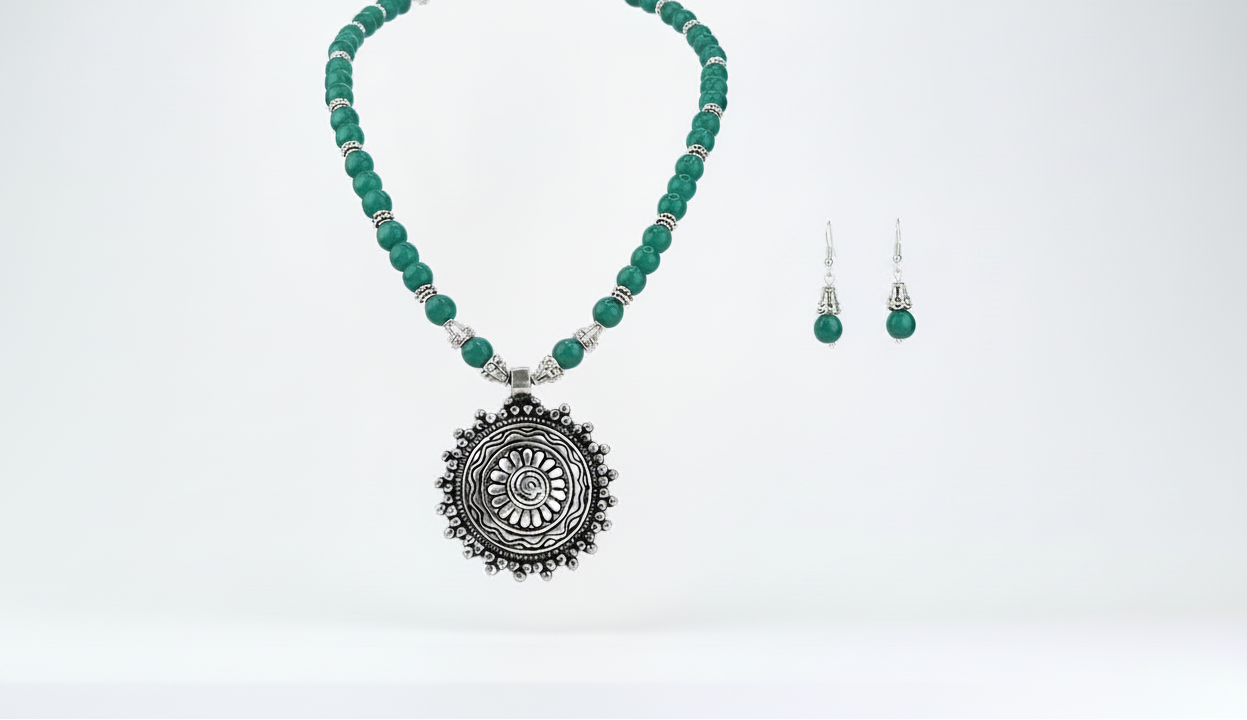 Jewelry set with green beaded pendant necklace and matching earrings on a white background