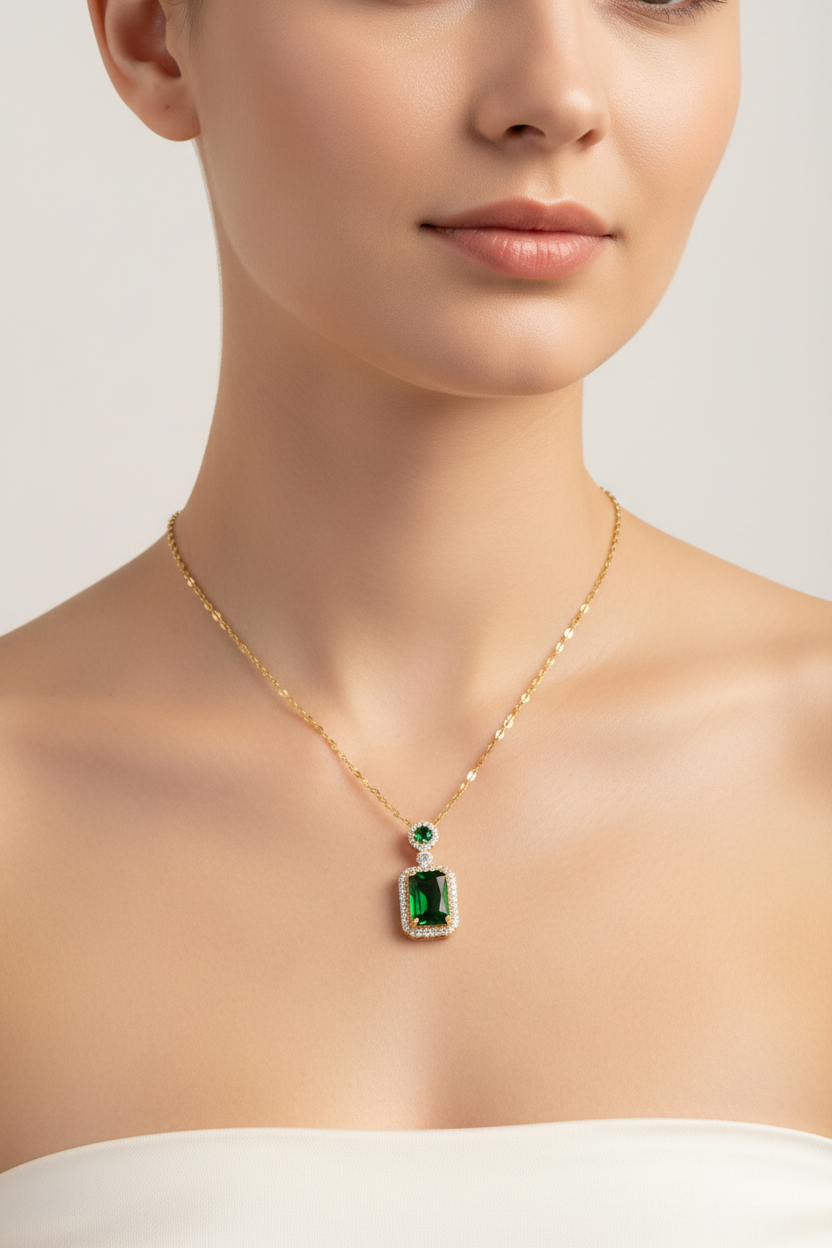 Gold necklace with a green gemstone pendant on a neutral background