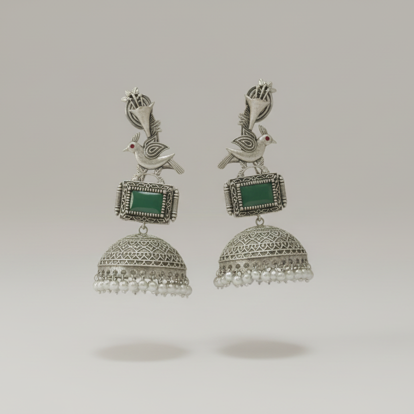 Pair of silver earrings with green stones on a light gray background