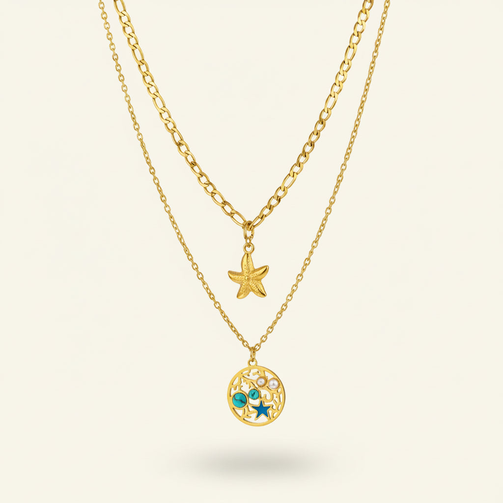 Two gold necklaces with starfish and circular pendants on a very light being stand.