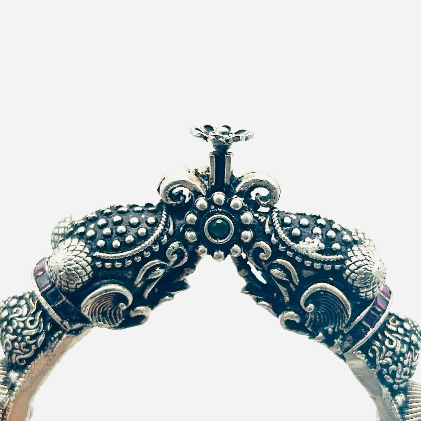 Decorative silver bangle with intricate designs on a white background