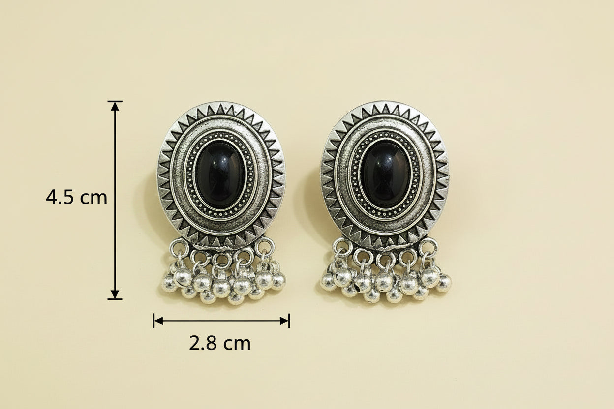 vintage chunky Pair of oxidize silver traditional earrings with black gemstones on a teal background