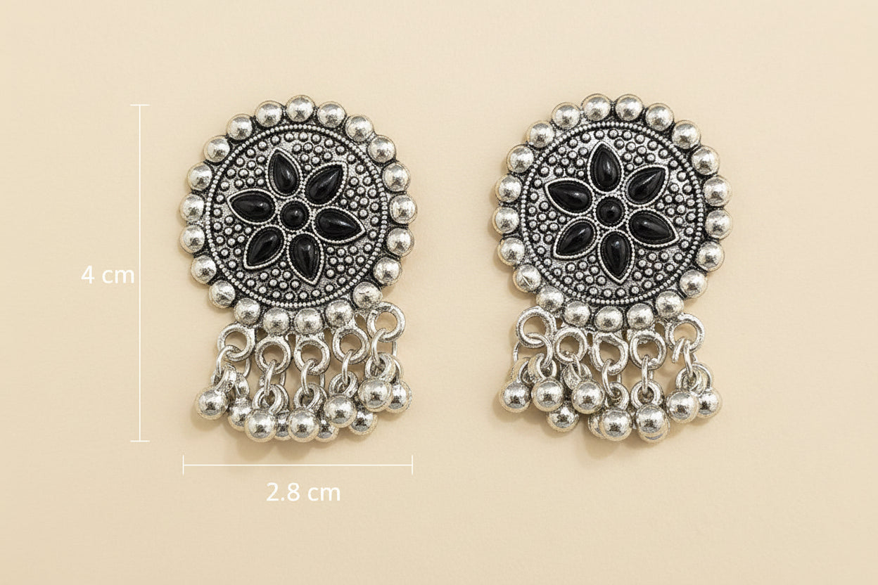 Pair of silver earrings with black center on a teal background