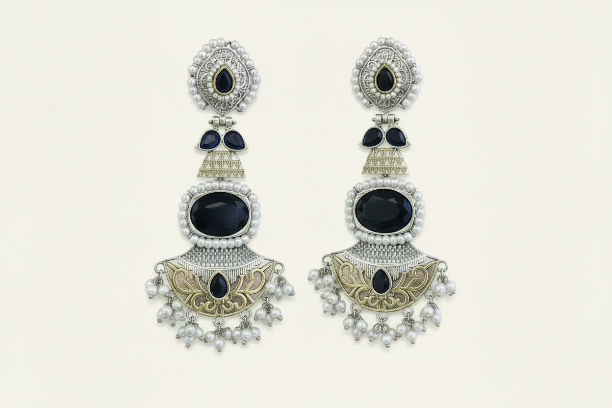 Pair of ornate earrings with black gemstones on a light background