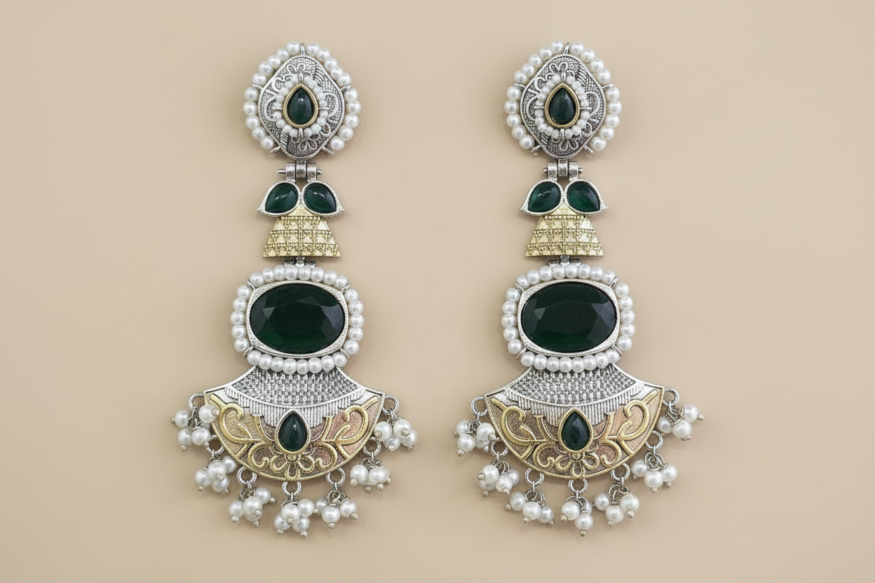 Pair of ornate earrings with green stones and pearl-like elements on a beige background