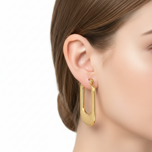 Gold hoop earrings worn by a model on a white background