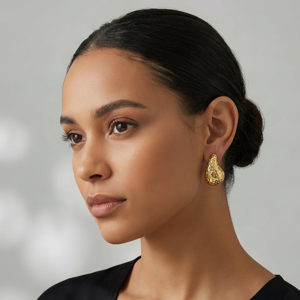 Woman wearing a gold earring against a neutral background