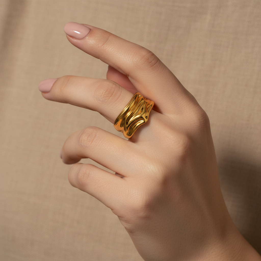 Hand wearing a gold ring on a beige background