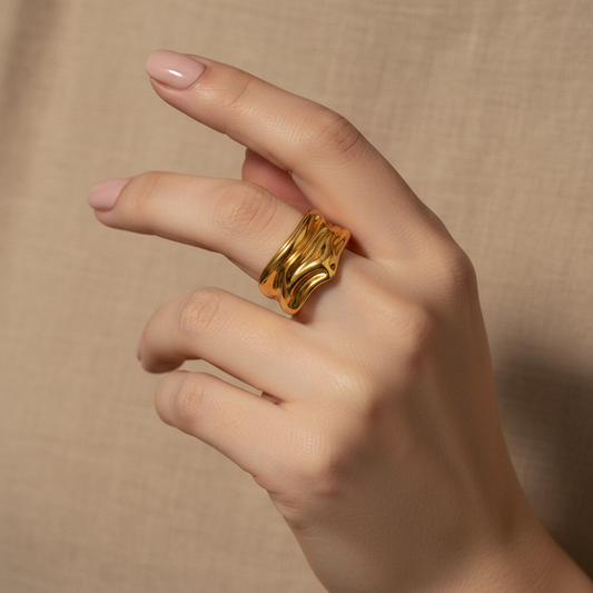 Hand wearing a gold ring on a beige background