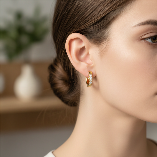Close-up of a person wearing gold hoop earrings with a blurred indoor background