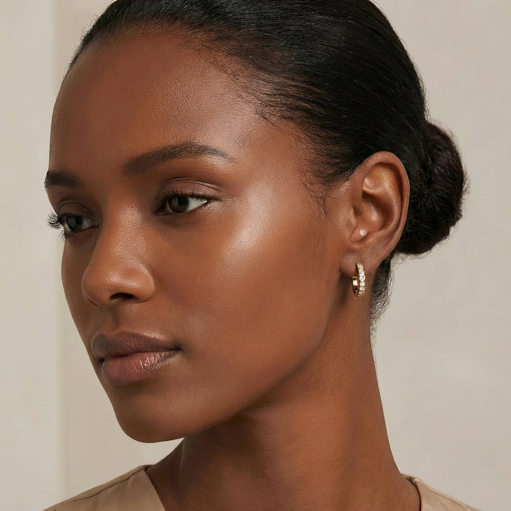 Close-up of a woman wearing gold hoop earrings with a neutral background