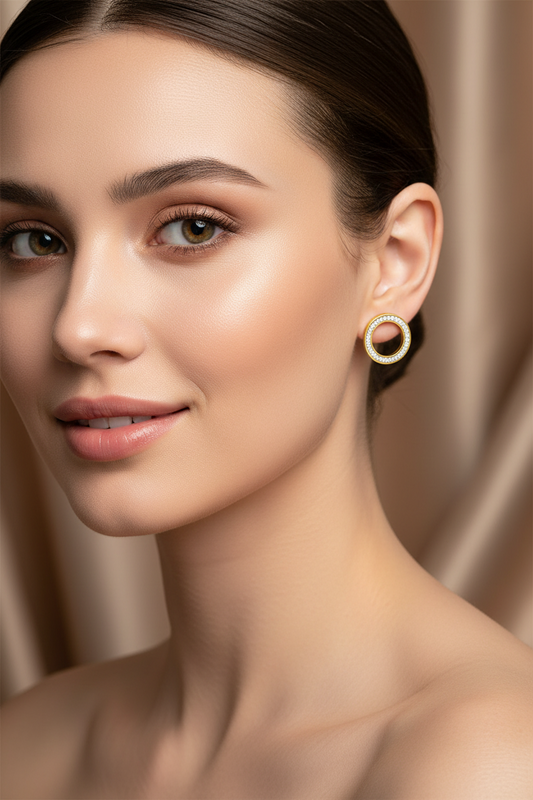 Close-up of a woman wearing gold hoop earrings with a neutral background