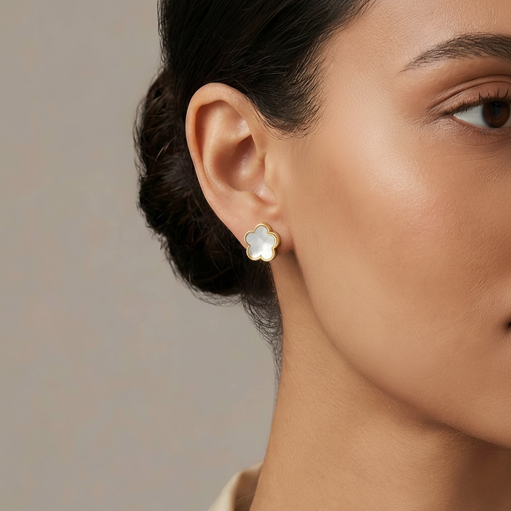 Close-up of a woman wearing a gold flower-shaped earring against a neutral background