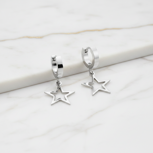 Silver star-shaped earrings on a marble surface