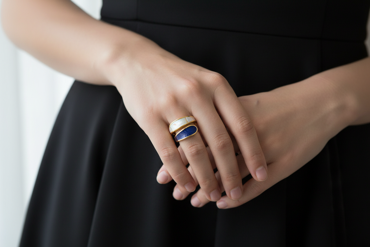 Close-up of hands wearing gold plated black and white band ring with a blurred background