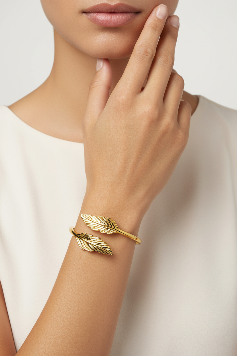 18k gold plated leaf bracelet on a person's wrist against a neutral background